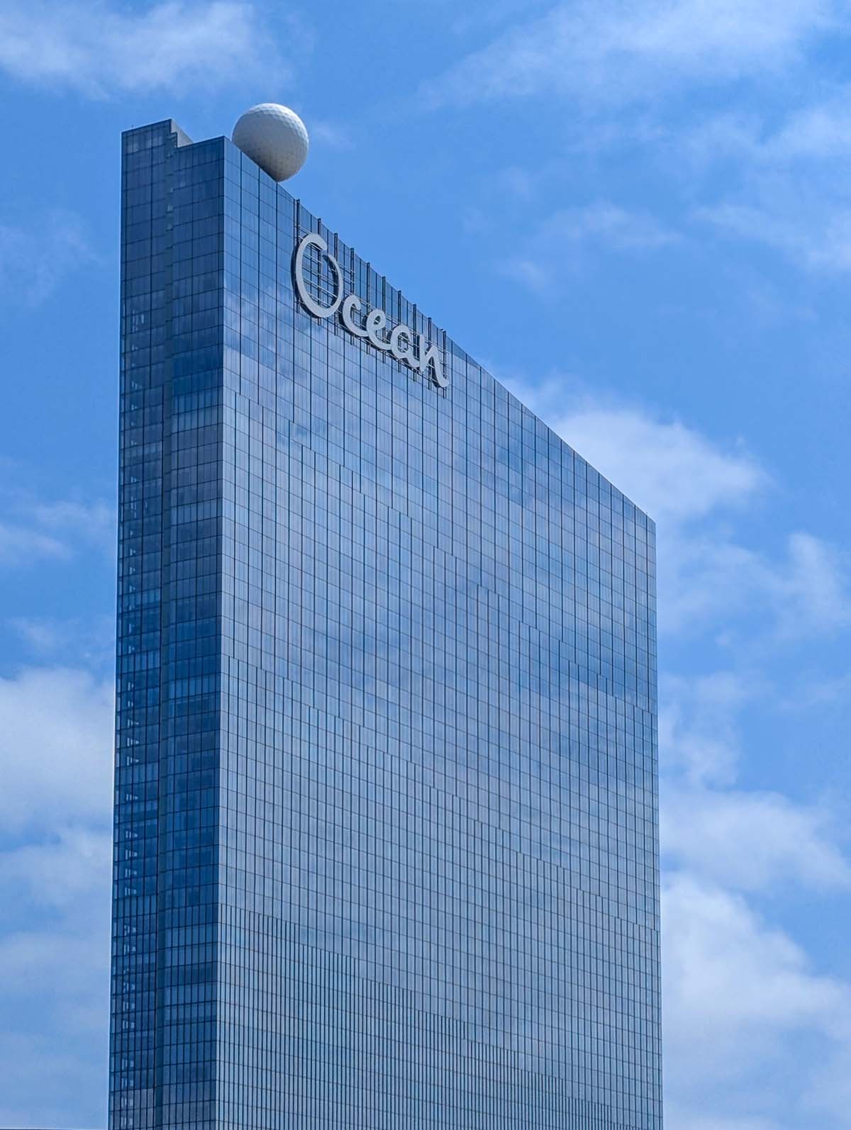 Tall glass Ocean Casino Resort tower against blue sky with white clouds