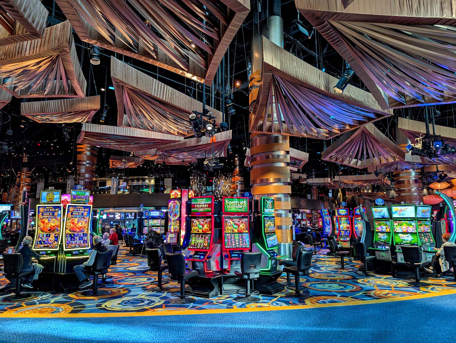 The casino at Ocean. Expansive gaming floor with high ceilings and art installations. Below rows of brightly lit slot machines.
