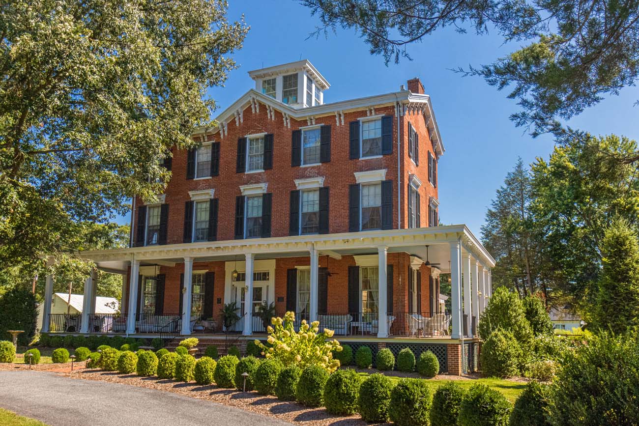 The 1860 brick Italianate Manor House at Brampton with its distinctive cupola, white columns, and wraparound porch, surrounded by manicured landscaping and mature trees.