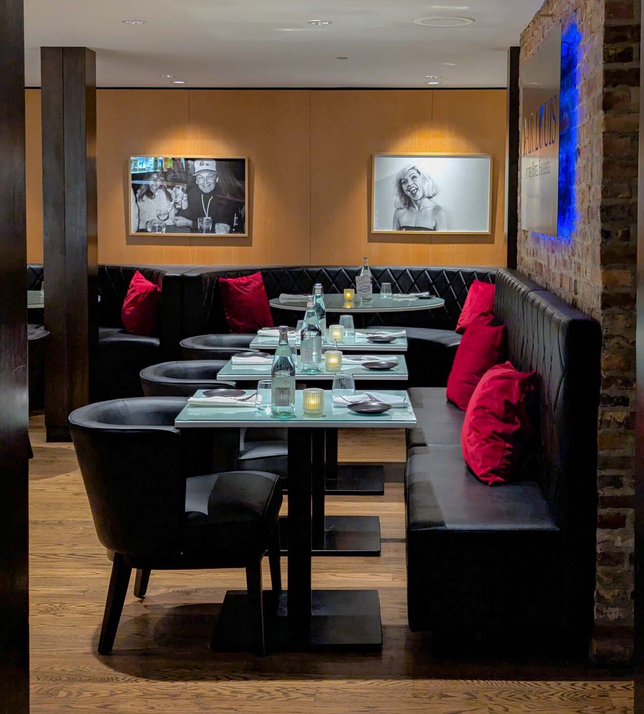 Intimate underground speakeasy dining room at Bar Louis featuring black leather tufted banquettes, red velvet pillows, Andy Warhol celebrity photographs by Christopher Makos, and modern lighting in historic Hotel Fauchere Milford PA