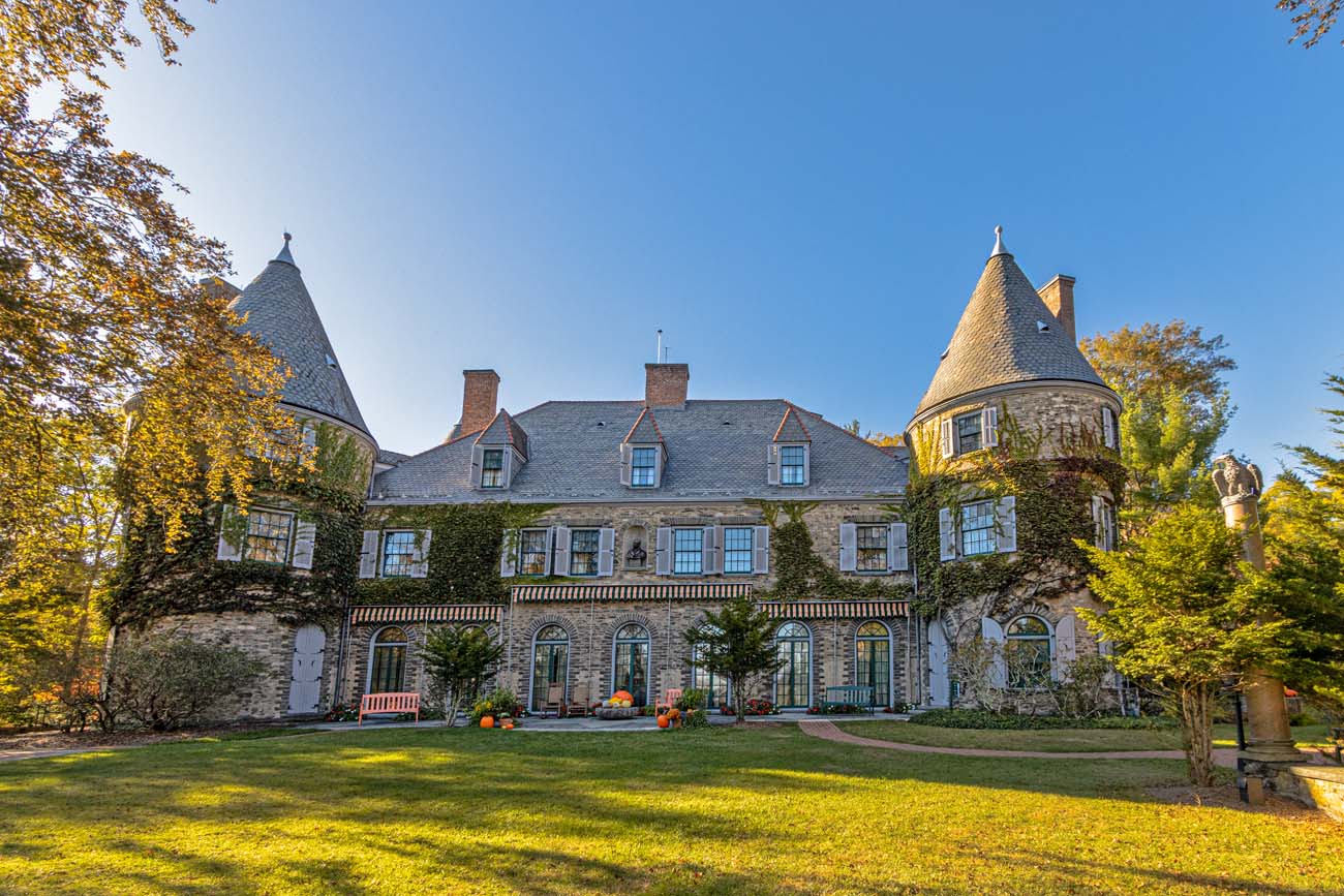 French chateau style Grey Towers National Historic Site mansion with stone turrets, ivy covered walls, manicured lawn, fall foliage and pumpkin decorations, former home of Gifford Pinchot in Milford Pennsylvania Pocono Mountains