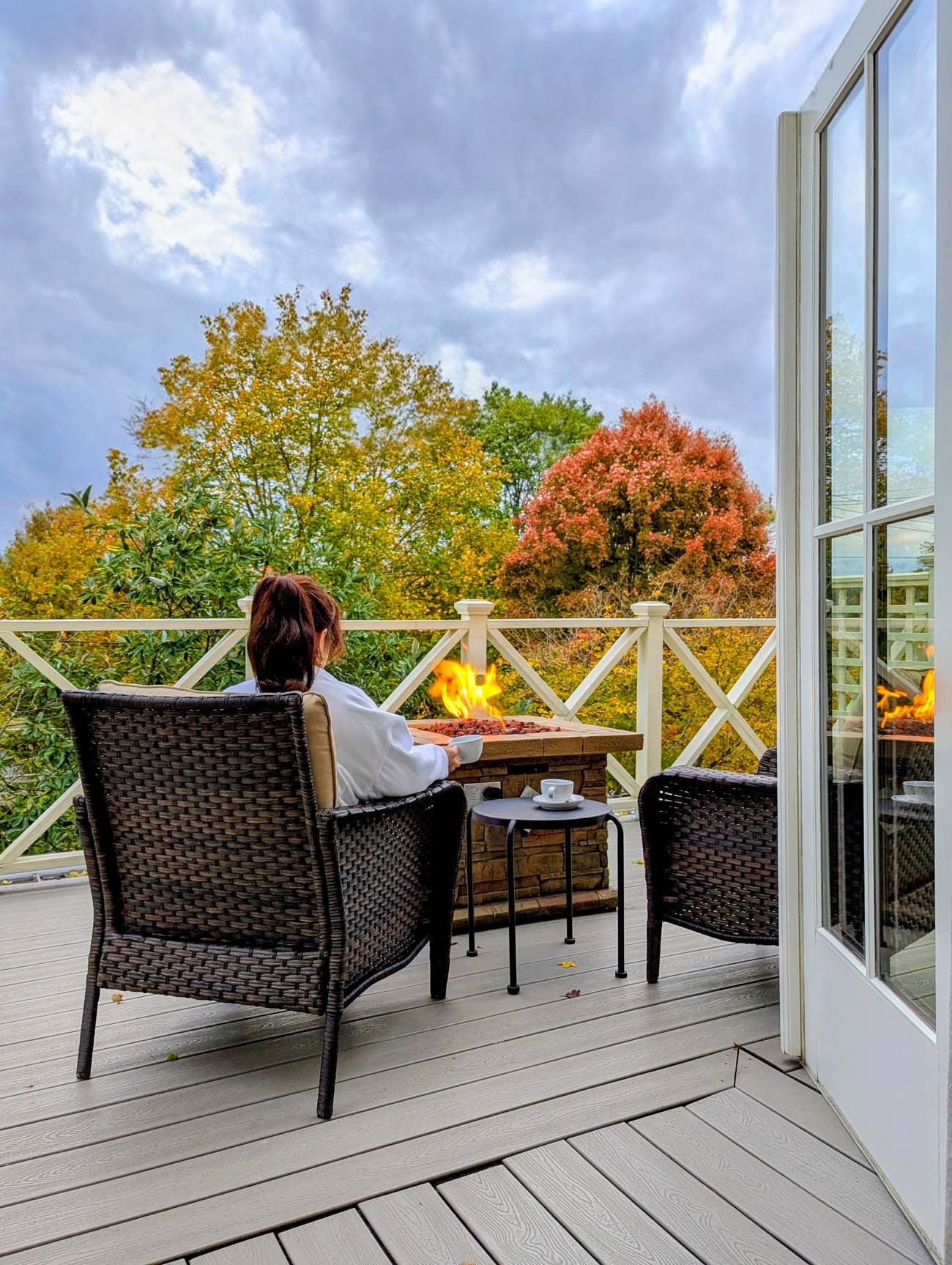 Guest relaxing on private balcony with gas firepit overlooking vibrant orange and yellow fall foliage trees at luxury boutique Hotel Fauchere in Milford Pennsylvania Pocono Mountains autumn getaway